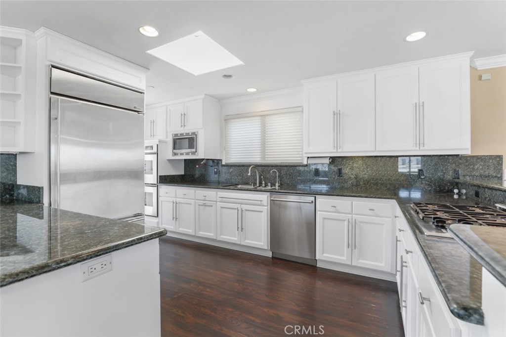 209 Crest Drive Manhattan Beach, CA 90266 - Photo 6 of 28 a kitchen with granite countertop a refrigerator a sink and white cabinets