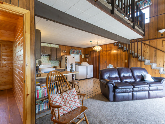 4770 Pine Crest Road Evanston, UT 82930 - Photo 21 of 24 Open-concept interior featuring wood paneling, a kitchen area with dark cabinetry, and an upper-level loft with a coordinating railing