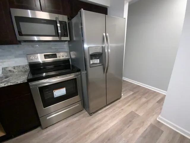 a kitchen with stainless steel appliances and wooden floor
