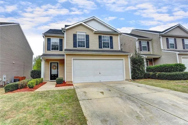 a view of a white house with large windows and a yard with plants