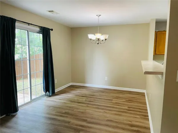 an empty room with wooden floor and chandelier