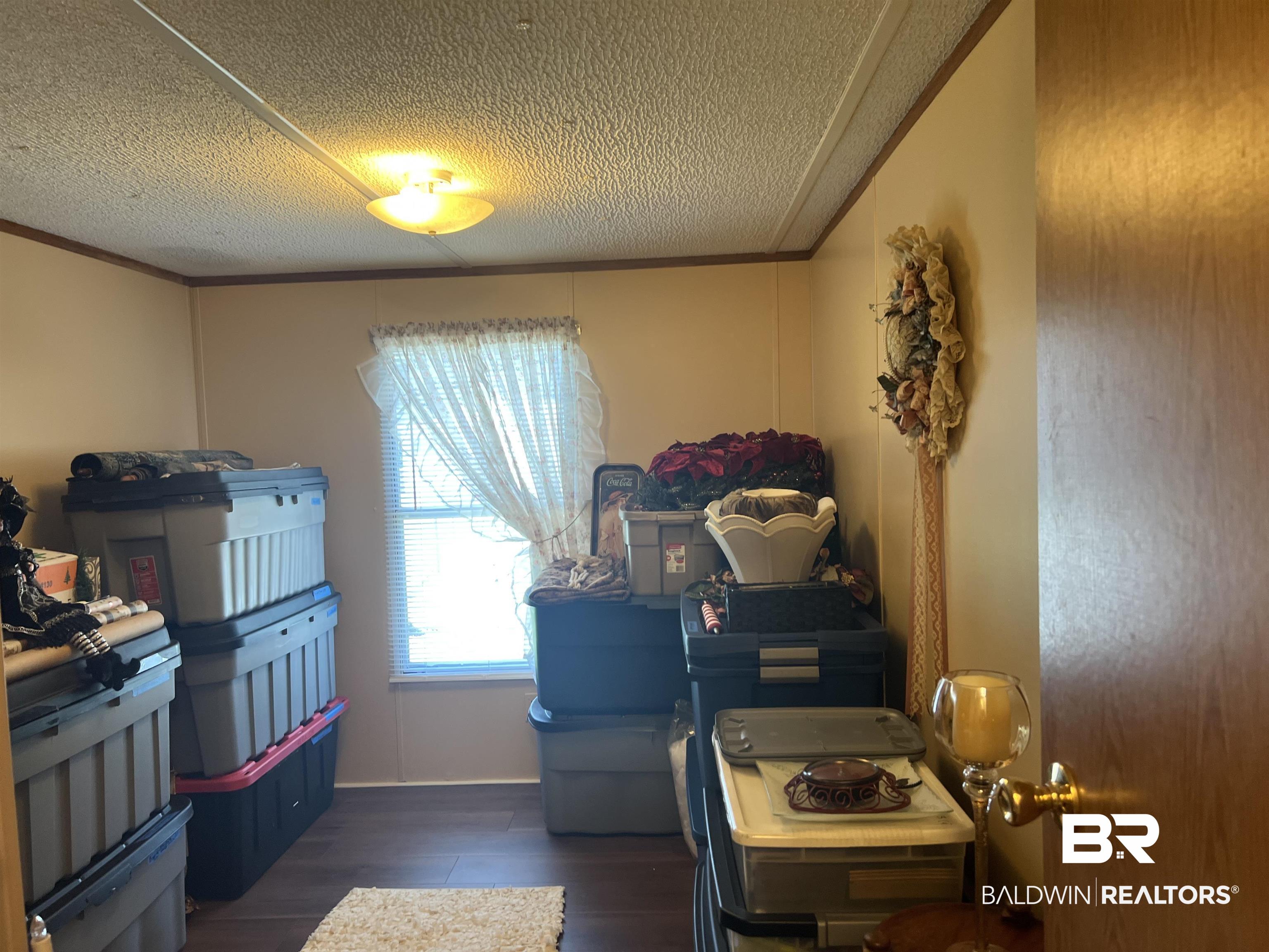 1177 McMillan Road Monroeville, AL 36460 - Photo 19 of 21 Laundry room with a textured ceiling, wood finished floors, and ornamental molding