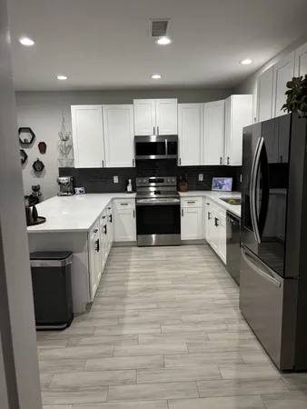 a large kitchen with stainless steel appliances granite countertop a stove top oven a refrigerator and a sink