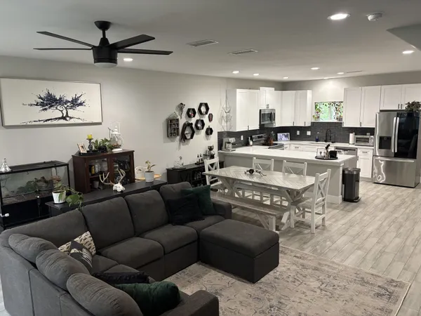 a living room with furniture kitchen view and a chandelier
