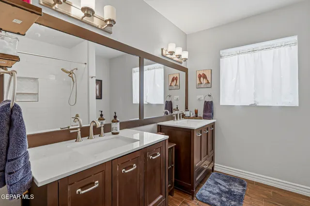 a bathroom with a granite countertop sink a large mirror and a shower