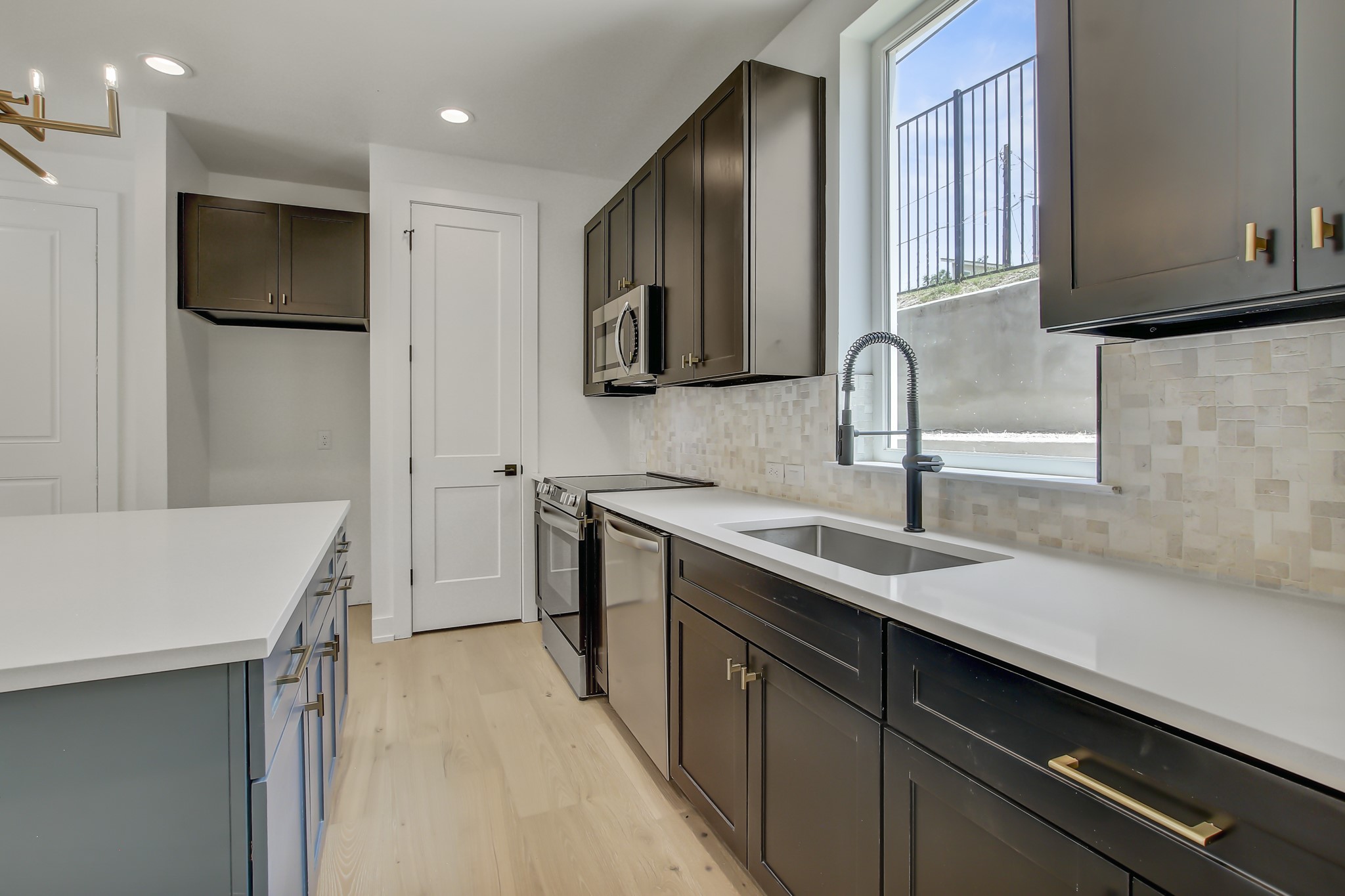 4127 East 12th Street, Unit 8 Austin, TX 78721 - Photo 5 of 32 Kitchen with a sink, stainless steel appliances, light wood-style floors, backsplash, and recessed lighting