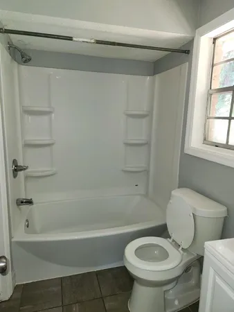 a white toilet sitting next to a bath tub