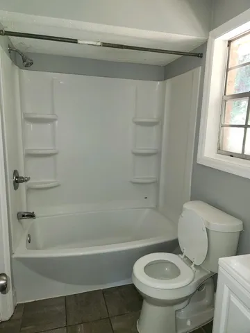 a white toilet sitting next to a bath tub