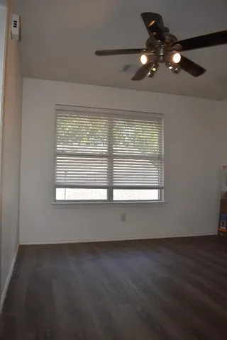 a view of an empty room with wooden floor and windows