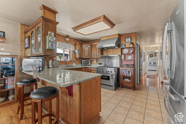 6407 North Dry Frk Cyn Road West Vernal, UT 84078 - Photo 23 of 48 Kitchen with stainless steel appliances, wall chimney exhaust hood, a peninsula, a sink, and brown cabinets
