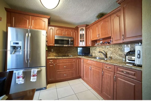 a kitchen with stainless steel appliances granite countertop a refrigerator a stove a sink and a microwave