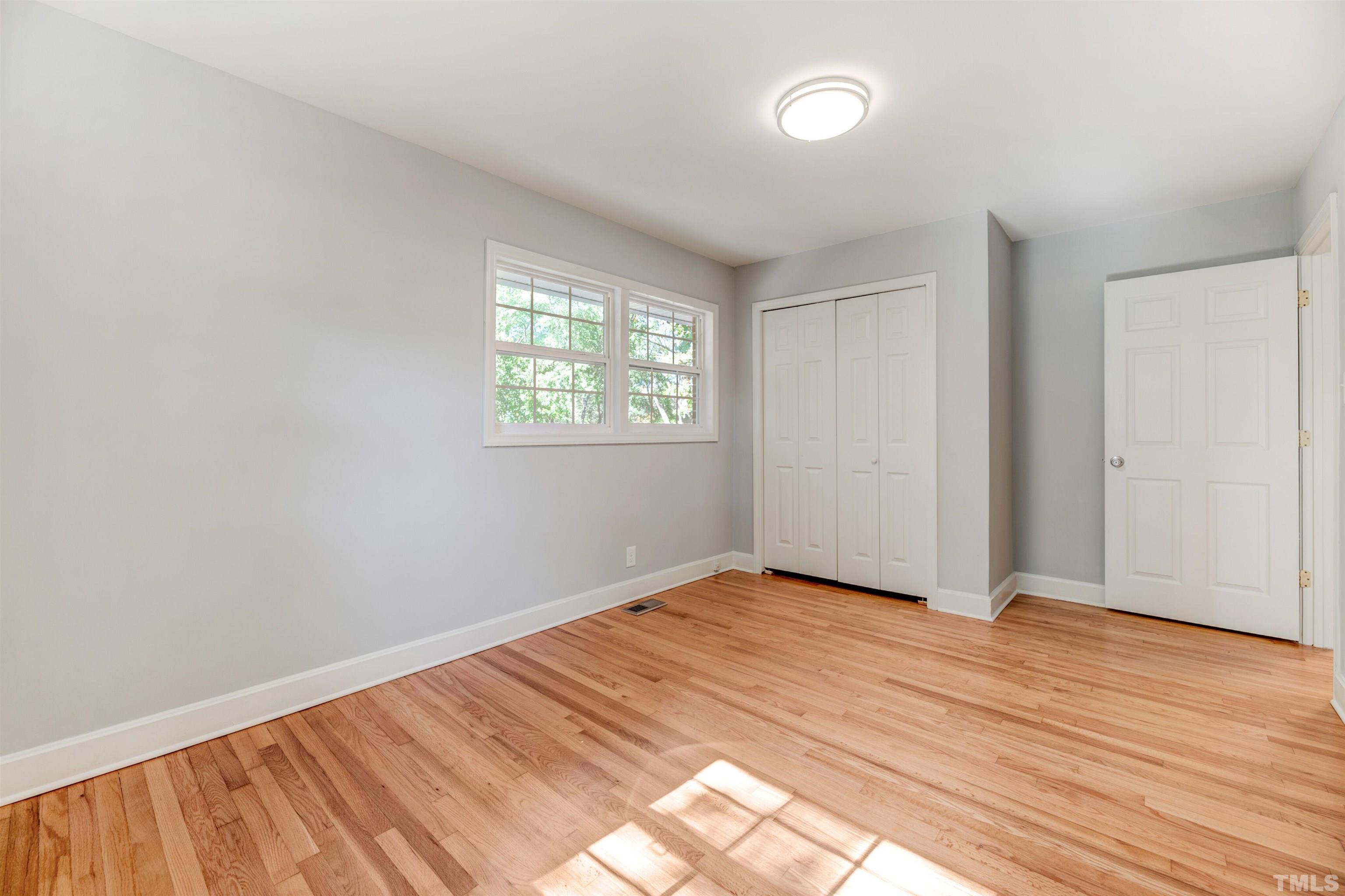 618 Starmont Drive Durham, NC 27705 - Photo 23 of 45 an empty room with wooden floor and windows