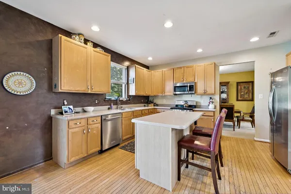 a kitchen with stainless steel appliances granite countertop a stove top oven a sink dishwasher a dining table and chairs with wooden floor