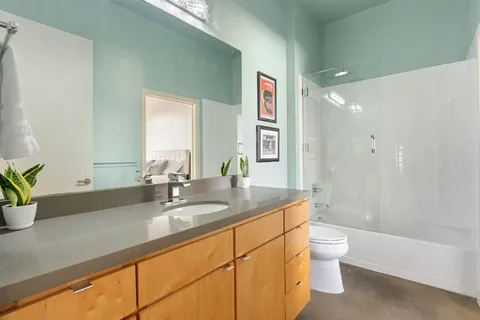 a bathroom with a granite countertop sink a toilet a mirror and bathtub