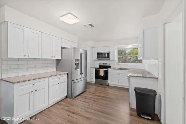 a kitchen with cabinets wooden floor and stainless steel appliances
