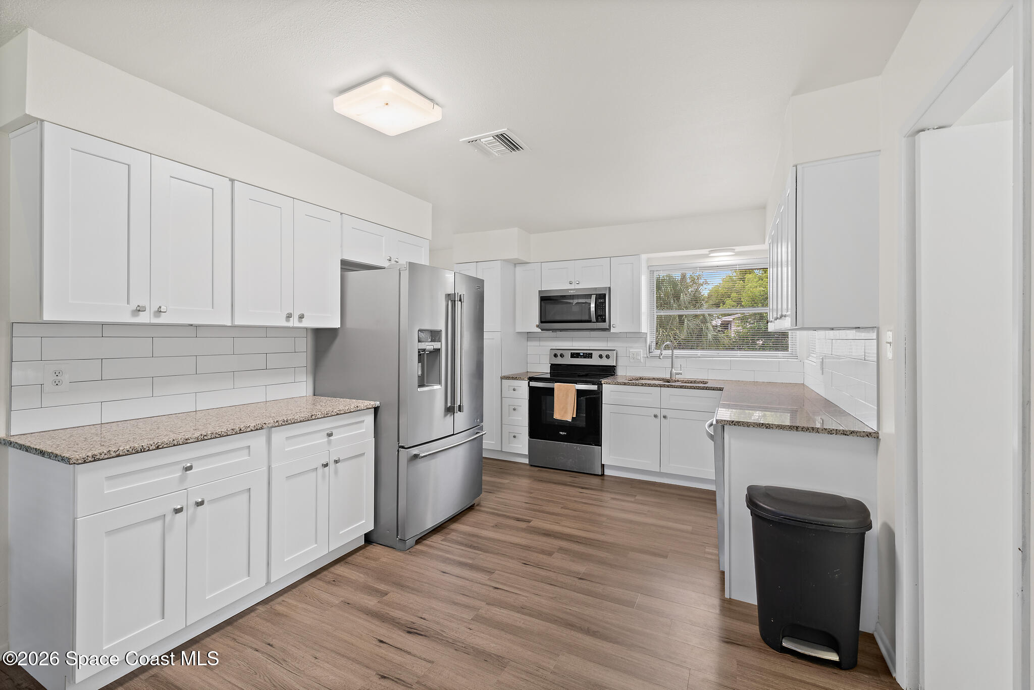 815 Glade Road Titusville, FL 32780 - Photo 3 of 30 a kitchen with cabinets wooden floor and stainless steel appliances