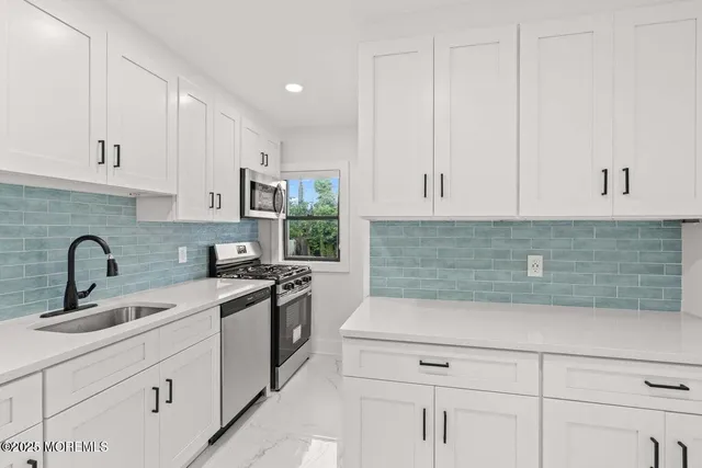 a kitchen with stainless steel appliances a stove a white cabinet and a microwave