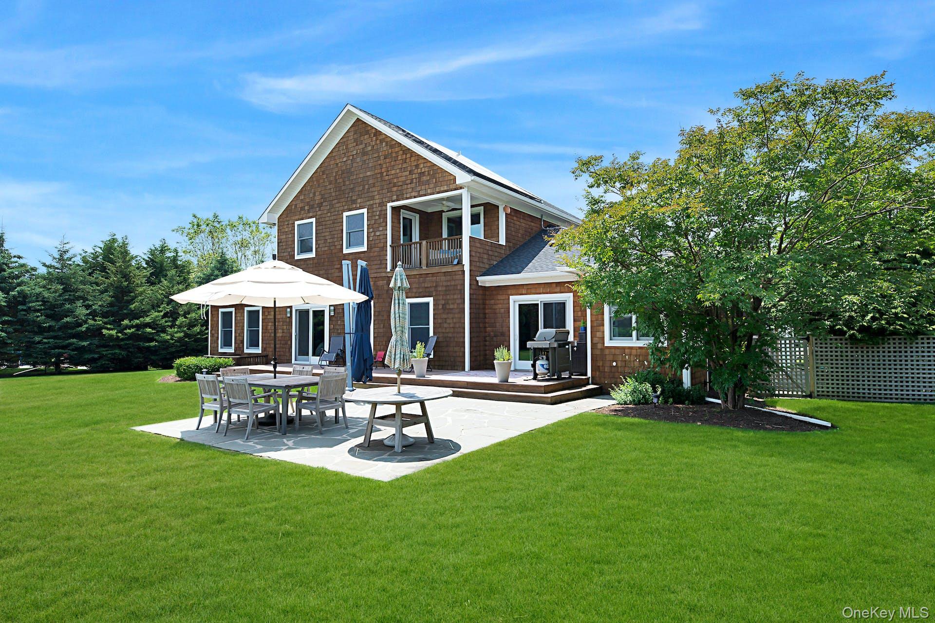 450 Sterling Woods Lane Southold, NY 11971 - Photo 34 of 41 a patio with table and chairs under an umbrella