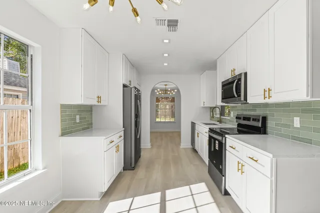 a kitchen with stainless steel appliances granite countertop a stove top oven a sink dishwasher and a refrigerator with wooden floor