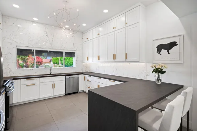 a kitchen with stainless steel appliances a white table chairs and a refrigerator