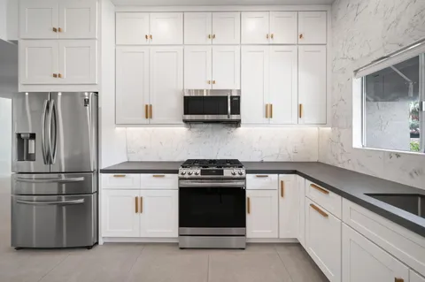 a kitchen with granite countertop white cabinets and stainless steel appliances