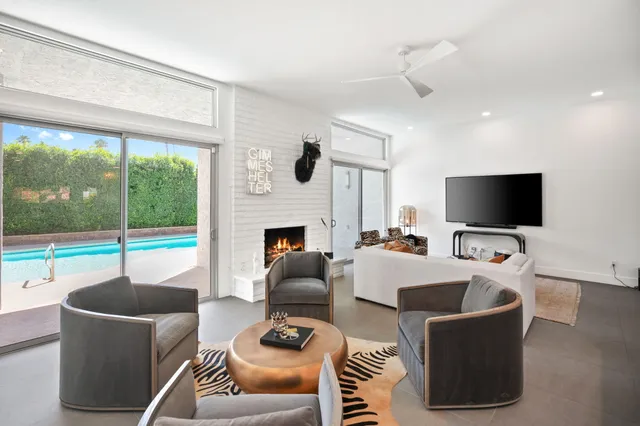 a living room with furniture a flat screen tv and a floor to ceiling window