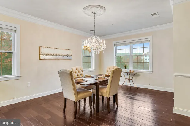 a kitchen with stainless steel appliances granite countertop a stove top oven a refrigerator a dining table and chairs with wooden floor