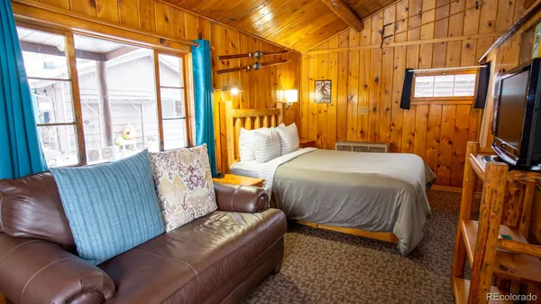 a bedroom with a bed couch and a flat tv screen next to a window