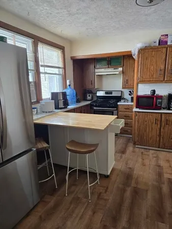 a living room with stainless steel appliances furniture a window and kitchen view