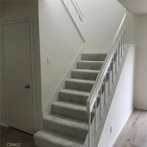 a view of staircase with wooden floor and white walls