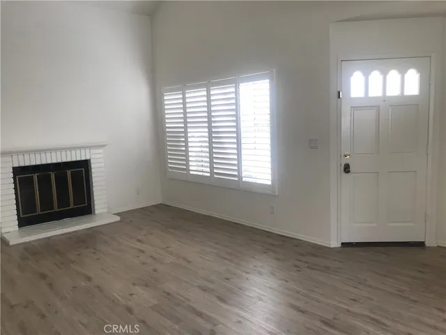 an empty room with wooden floor a fireplace and windows