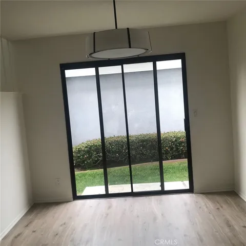 a view of an empty room with wooden floor and a floor to ceiling window