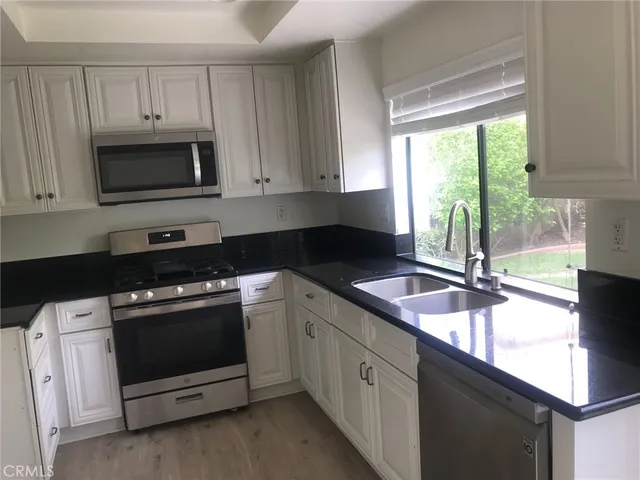 a kitchen with granite countertop a sink stove and microwave