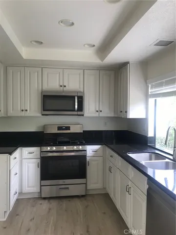 a kitchen with stainless steel appliances granite countertop a sink a stove a microwave and cabinets