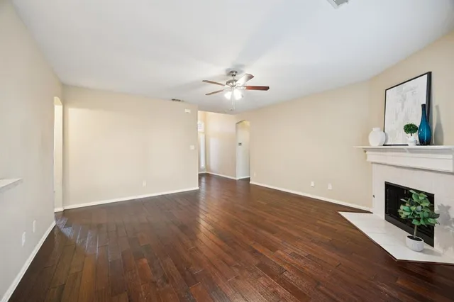 a view of an empty room with wooden floor and a fireplace