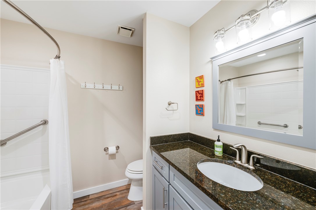230 Cut-Off Road, Unit 101 Port Aransas, TX 78373 - Photo 15 of 30 a bathroom with a granite countertop sink toilet a mirror and shower