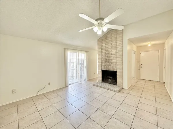 an empty room with fireplace and chandelier fan