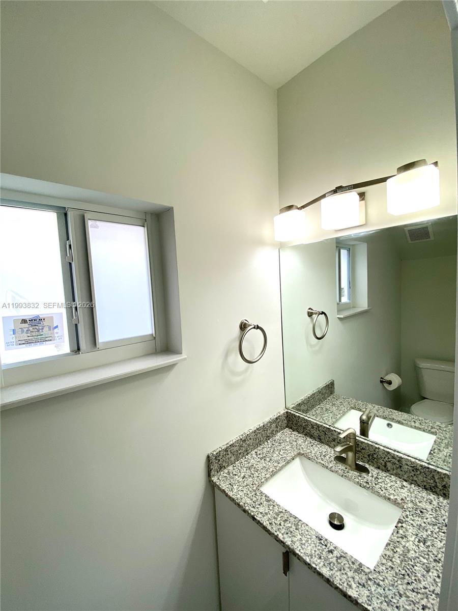 5860 Lincoln Street, Unit 5860 Hollywood, FL 33021 - Photo 2 of 21 a bathroom with a granite countertop sink a mirror and a window