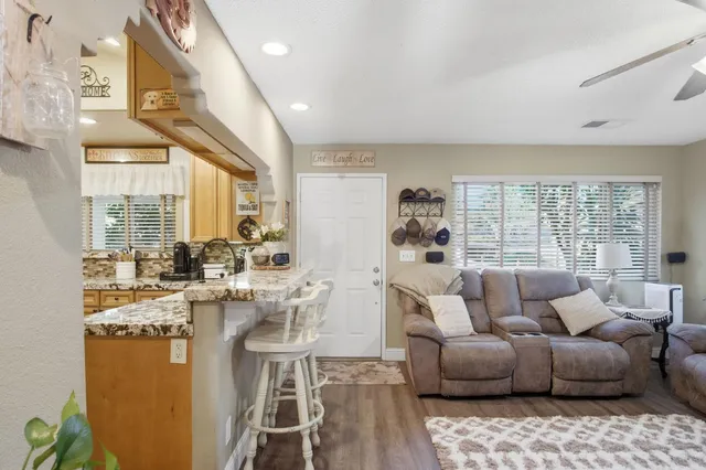 a living room with furniture large windows and wooden floor