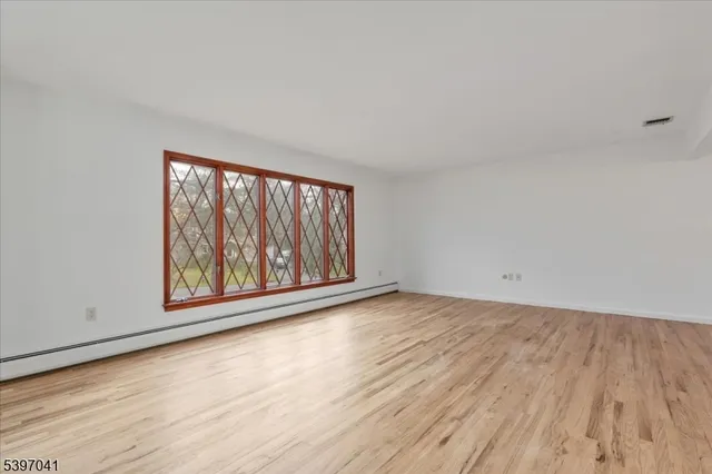 a view of an empty room with a window and wooden floor
