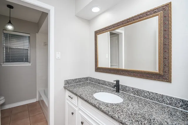 a bathroom with a granite countertop sink and a mirror