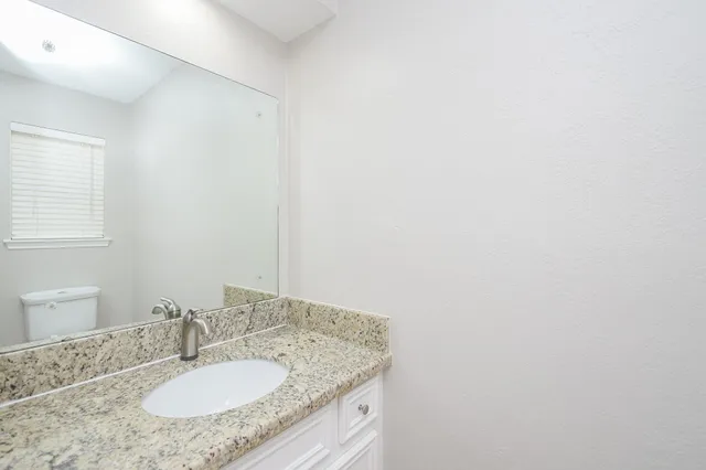 a bathroom with a granite countertop sink and a mirror