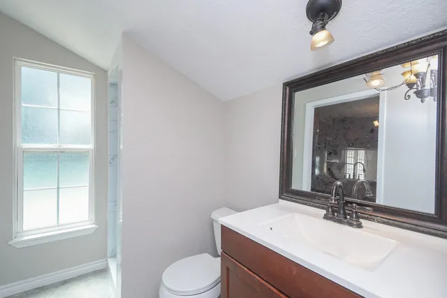 a bathroom with a sink a toilet a mirror and window