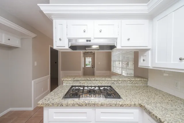 a kitchen with granite countertop a sink a stove and cabinets