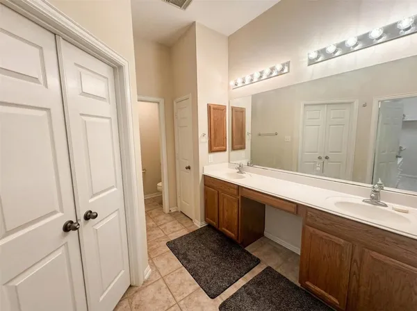 a spacious bathroom with a double vanity sink a mirror and a shower
