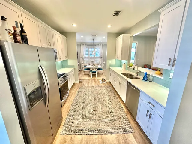 a large kitchen with kitchen island a large counter top space a sink a window and stainless steel appliances
