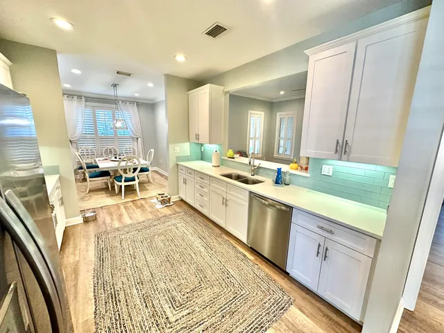 a kitchen with stainless steel appliances a refrigerator a sink a stove a microwave a dining table and chairs