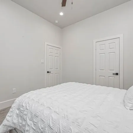 a bedroom with a large bed chandelier and a large window