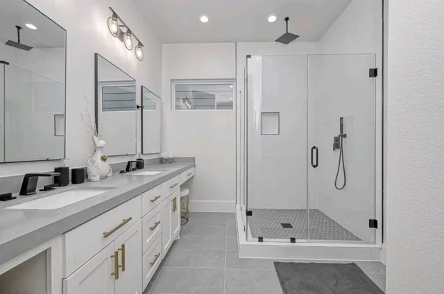 a bathroom with a double vanity sink mirror and shower