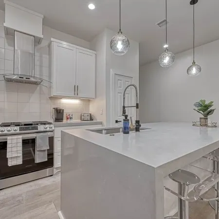 a kitchen with stainless steel appliances granite countertop a sink a stove a dining table and chairs